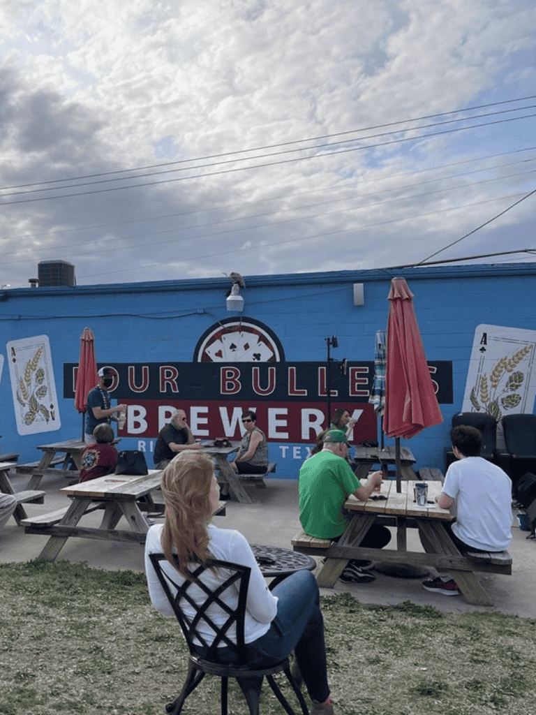 Outdoor brewery patio with picnic tables and customers enjoying drinks at Porter Brews, Texas.