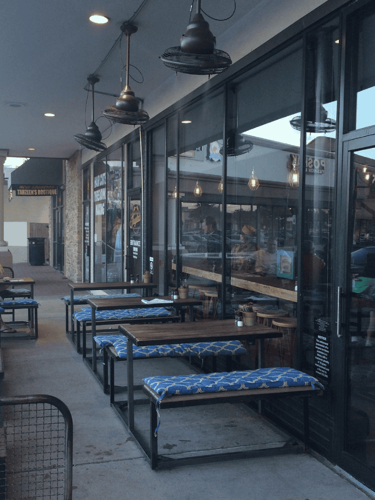 Modern outdoor dining area at QuestForDirections restaurant with stylish bench seating and glass window walls.