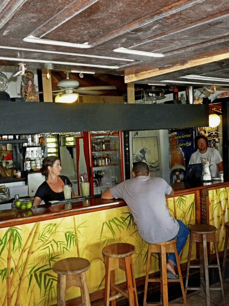 Cozy bar scene with tropical décor and customers enjoying drinks at QuestForDirections restaurant.