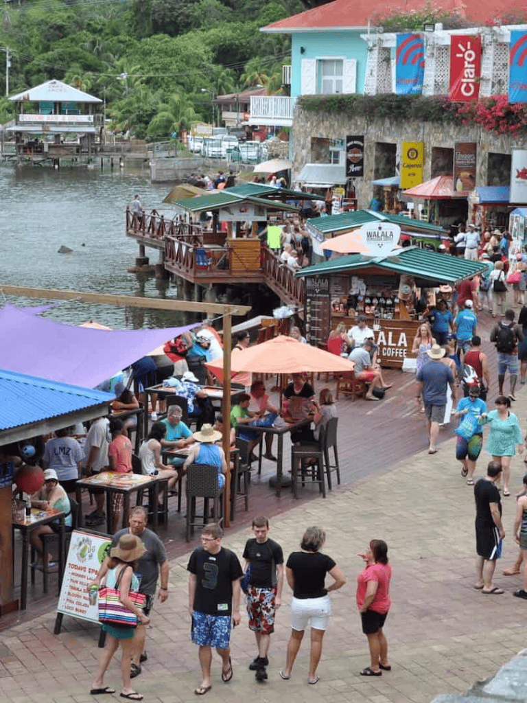 Relaxing waterfront cafe in a lively tropical town, vibrant crowds and colorful umbrellas.