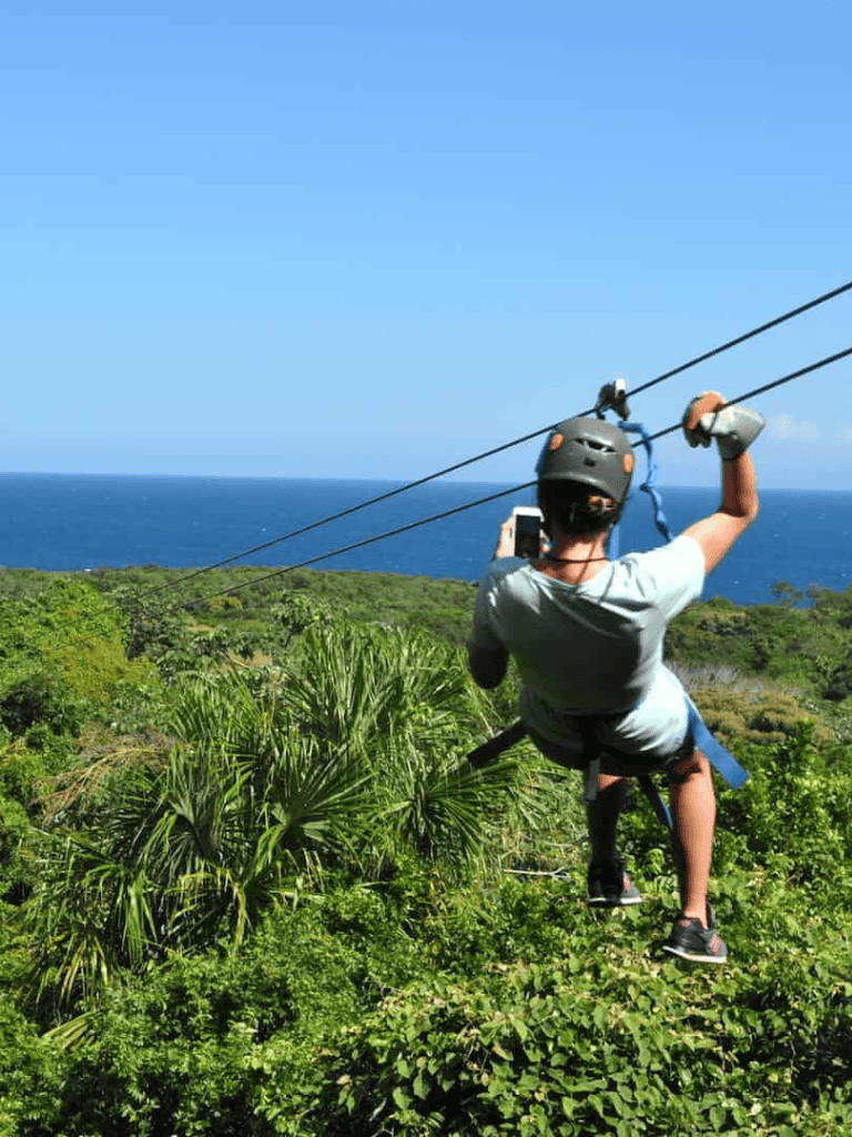 Thrilling zip line adventure over lush greenery with ocean view for outdoor enthusiasts.