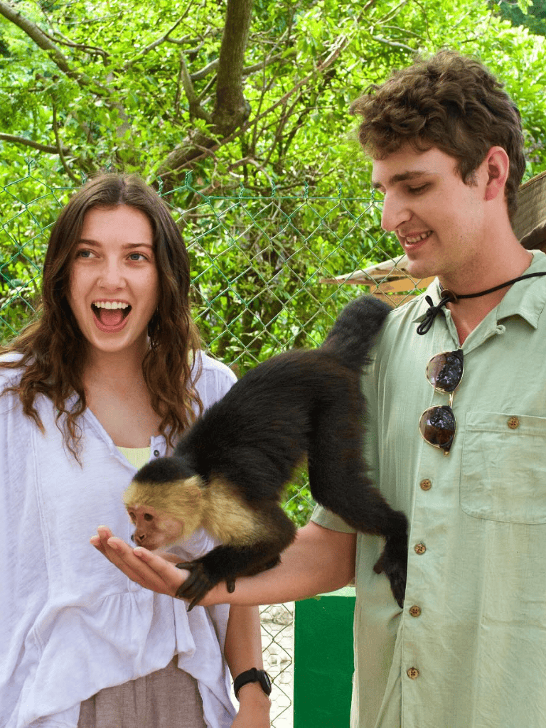 Cute girl smiling with a monkey at QuestForDirections zoo attraction.
