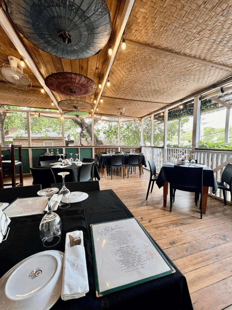 Relaxed outdoor dining area with elegant table settings and bamboo ceiling at Quest for Directions restaurant.