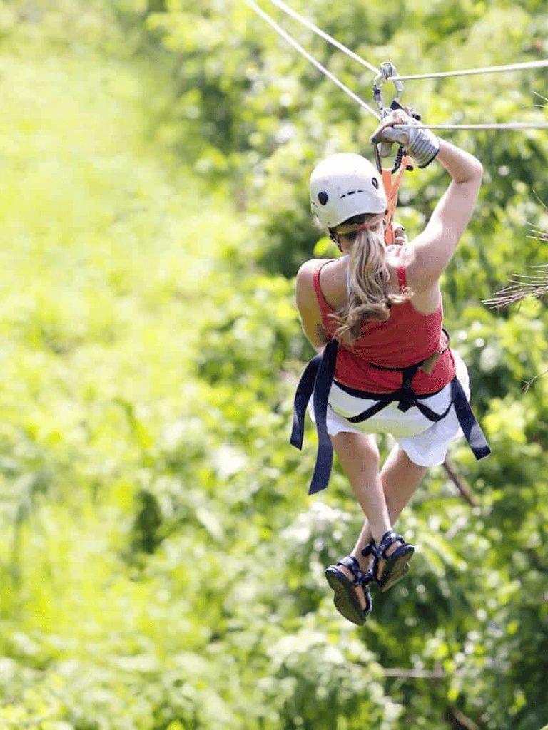 1. Person zip lining through lush green forest during outdoor adventure.