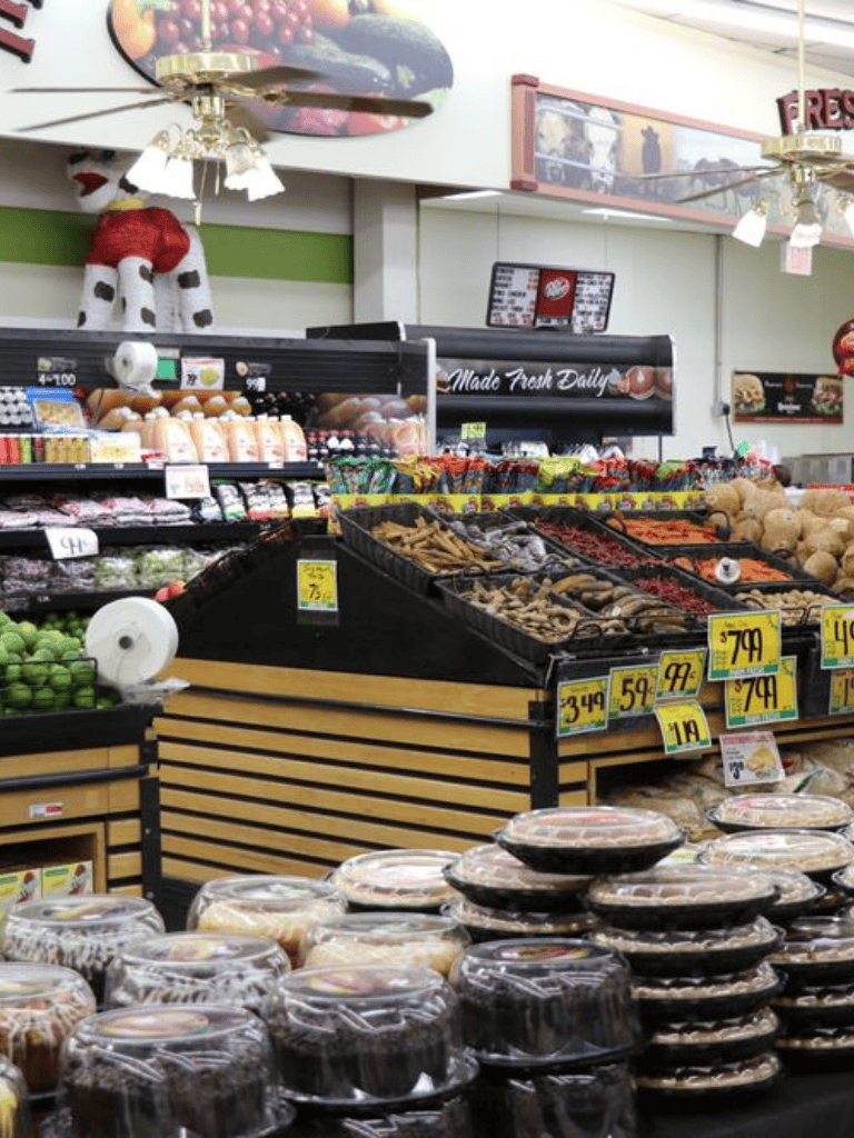Bright supermarket produce section with fresh fruits, vegetables, and baked goods for seasonal holiday shopping.
