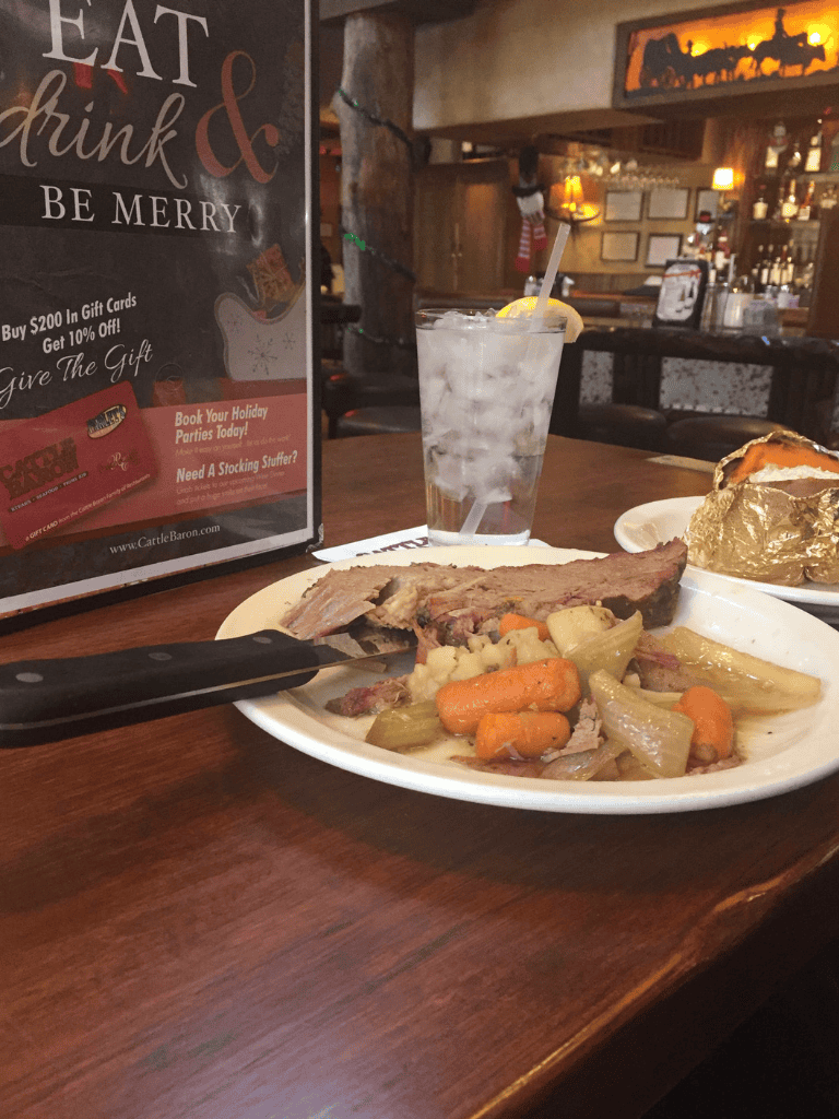 Juicy steak with vegetables and a refreshing iced drink at a cozy restaurant.