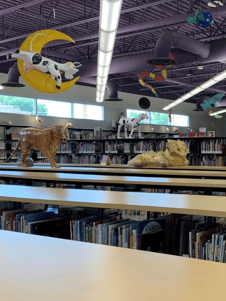 Whimsical animal sculptures in a colorful library with space-themed ceiling decorations.