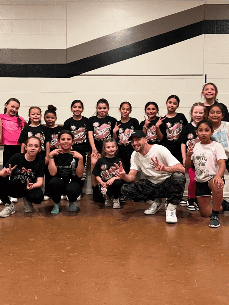 Joyful dance team group photo with kids and coach at QuestForDirections event, celebrating success and teamwork.