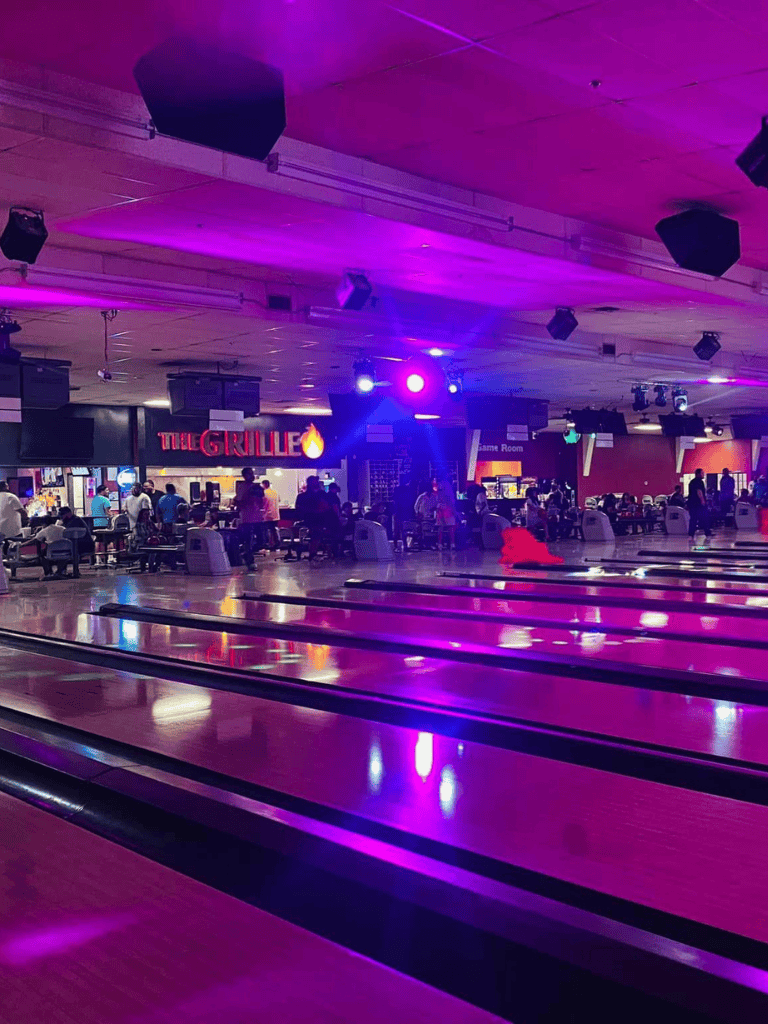 Brightly lit bowling alley with neon purple lights and multiple bowling lanes for entertainment and fun.
