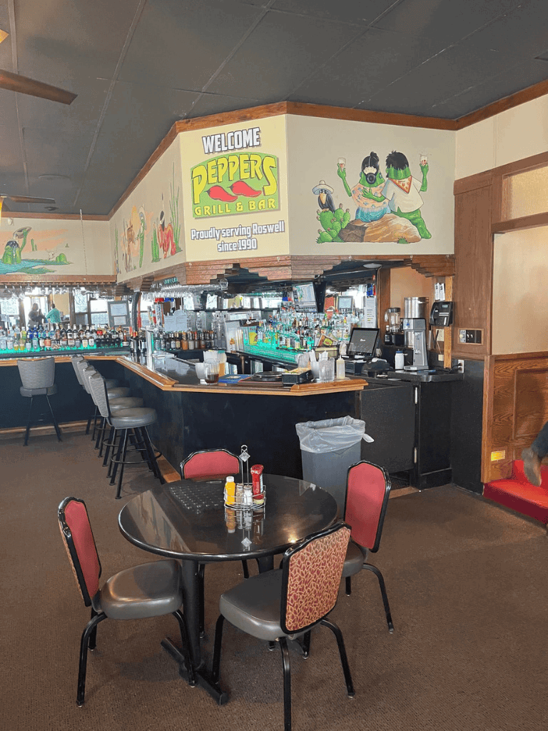 Colorful bar area with a mural, casual dining setup at Peppers Grill & Bar in Roswell.