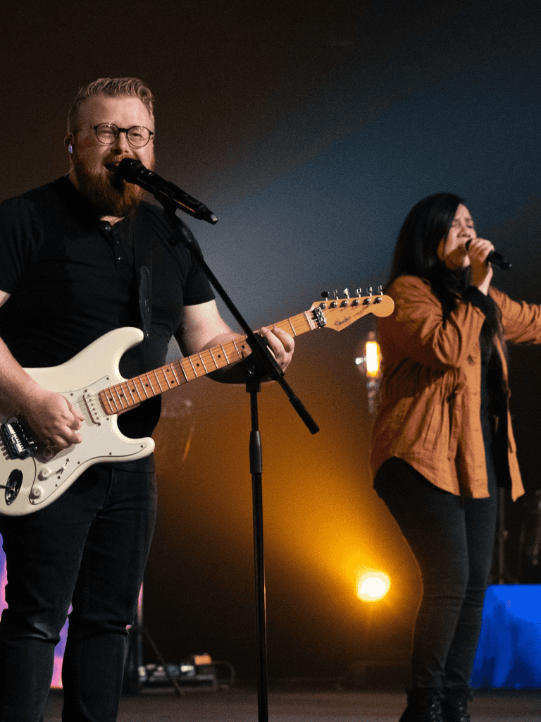Playing live music at a concert with singer and guitarist on stage.