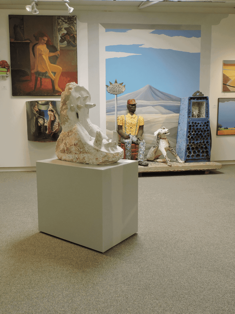 Colorful art sculptures and paintings displayed in an art gallery, representing diverse artistic styles and cultural themes.