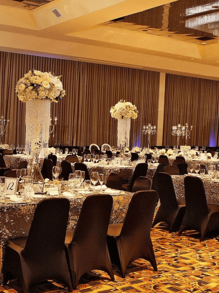 Elegant banquet hall decorated for wedding reception with tall floral centerpieces and sparkling table settings.