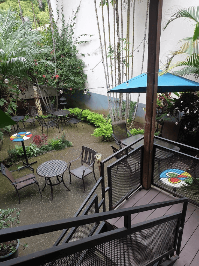 Cozy outdoor garden seating with tables, chairs, string lights, and vibrant plants. Perfect for relaxing or socializing.