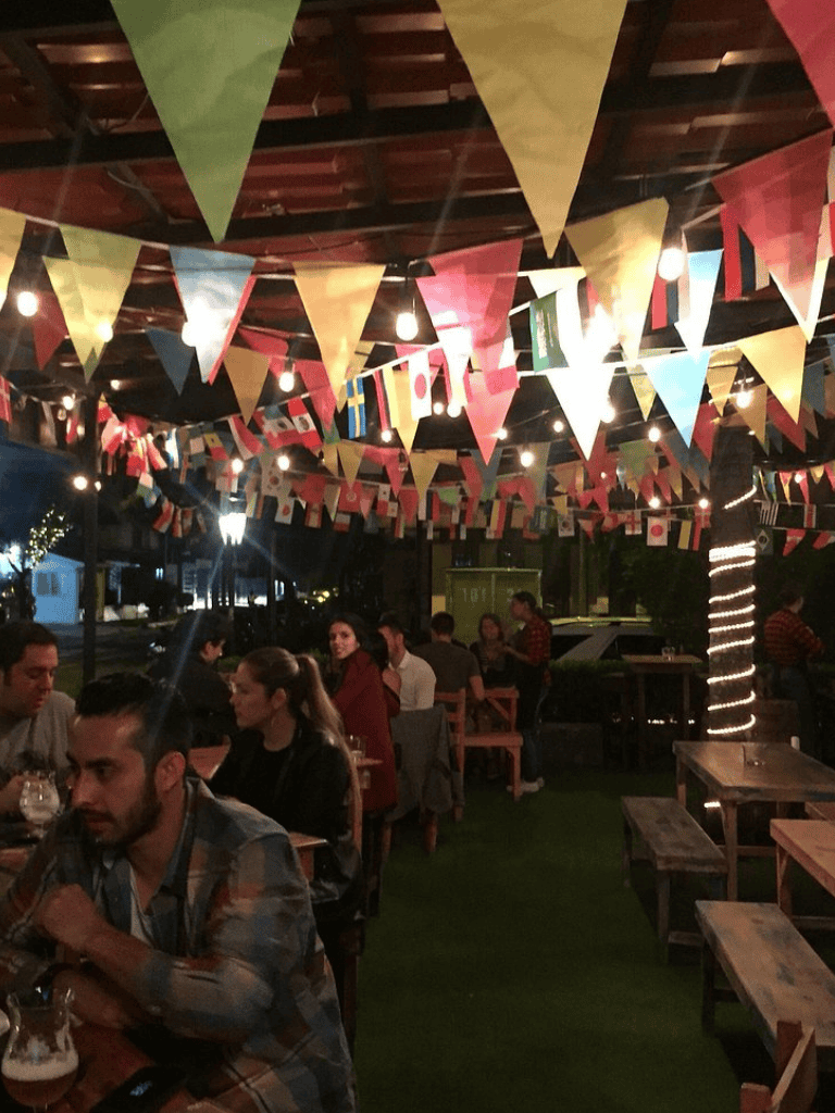 Colorful international flags and festive bunting at outdoor restaurant, lively atmosphere, evening dining, QuestForDirections.