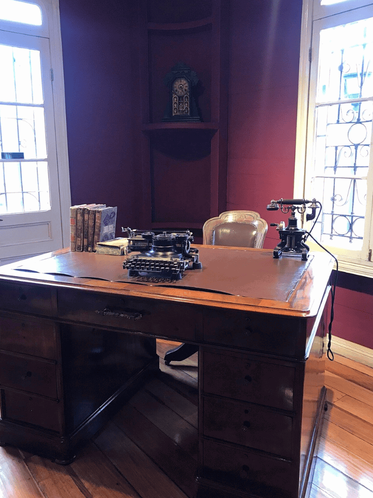 Desk with vintage telephone and books in historic office setting.