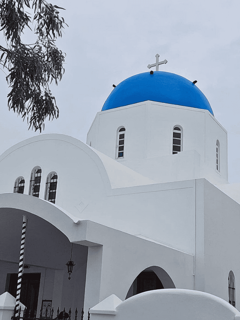 Traditional Greek church with iconic blue dome and white architecture in Santorini.