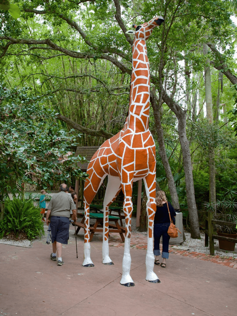Colorful giraffe sculpture in lush outdoor setting, popular attraction at QuestForDirections.