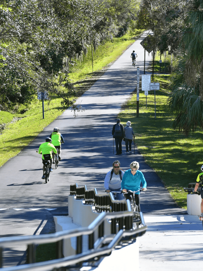 Pedestrian and bike-friendly trail in Florida with walkers and cyclists enjoying nature.