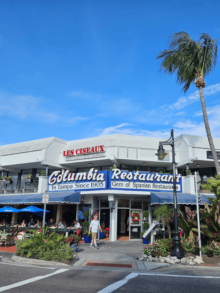 Outdoor view of Columbia Restaurant in Tampa, Florida, featuring vibrant signage and palm trees.