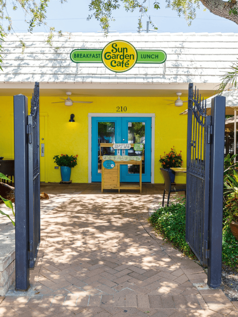 Bright yellow cafe exterior with blue doors, welcoming outdoor entrance for breakfast and lunch at Sun Garden Café.