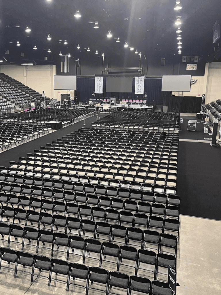 Empty conference room with chairs set up for event and stage setup.
