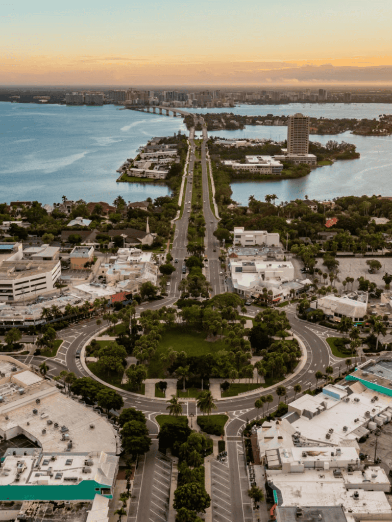 Aerial view of downtown Fort Lauderdale with lush parks, waterways, and waterfront buildings at sunset.