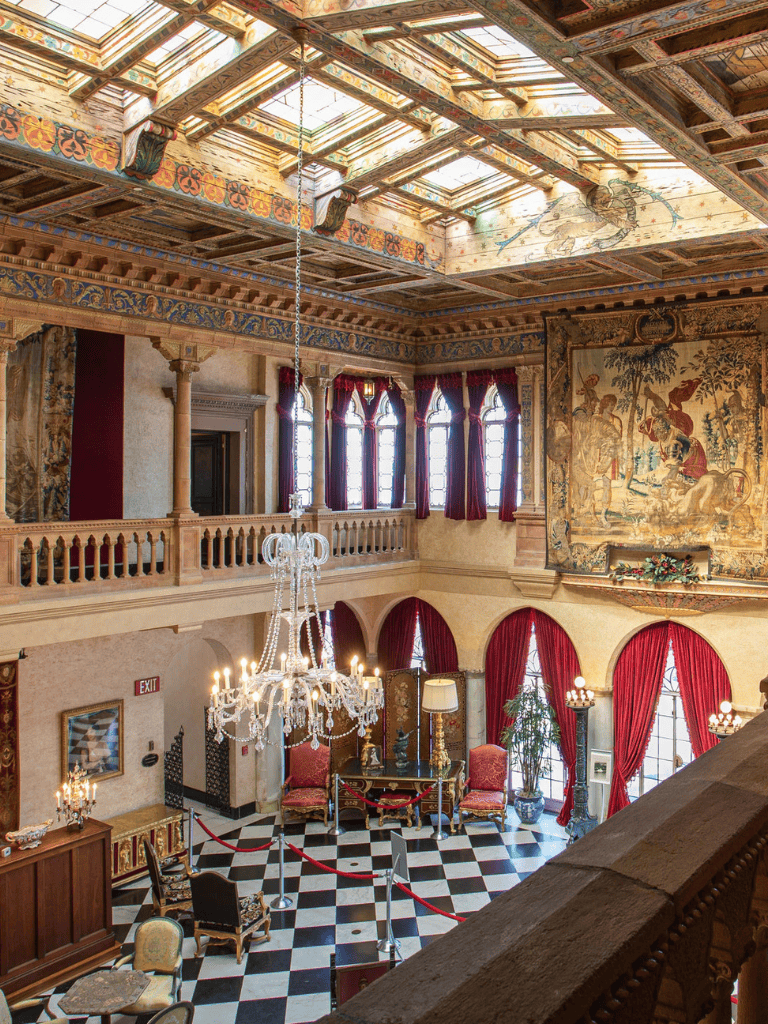 Intricate historic hotel ballroom with chandeliers, ornate drapes, and vintage decor.