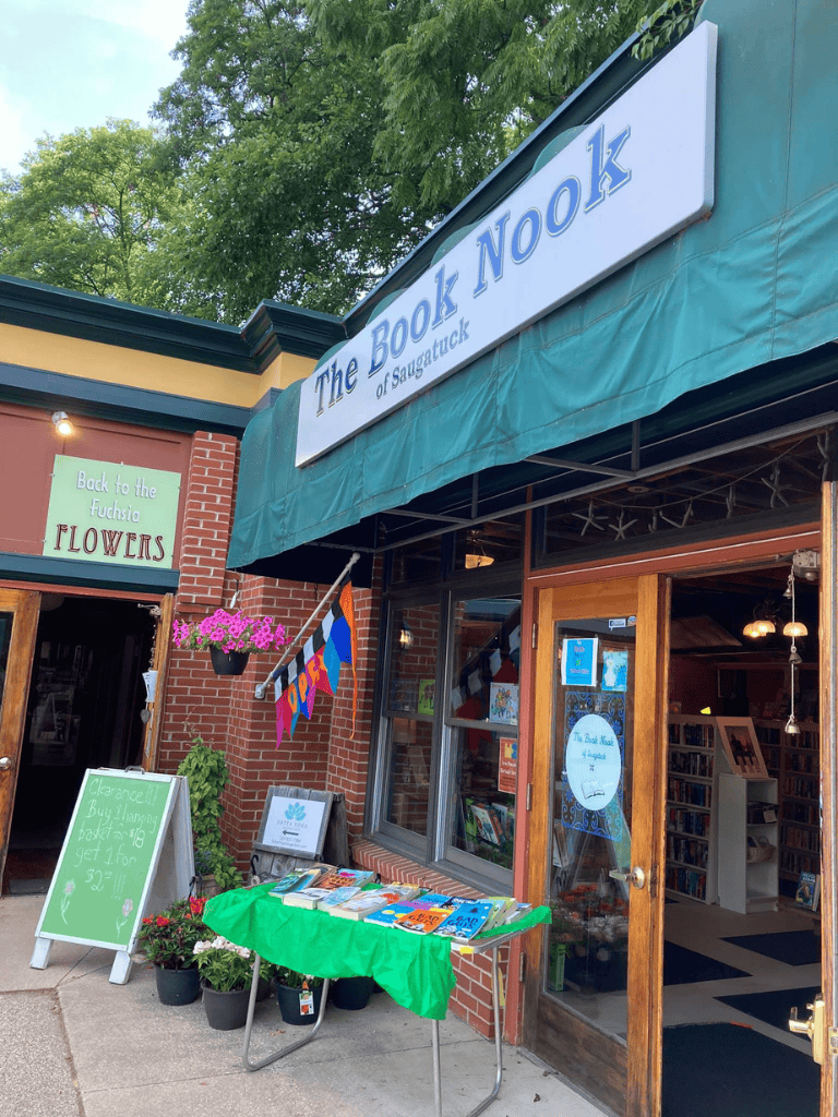 Cozy bookstore in Saugatuck with outdoor book table and floral display.