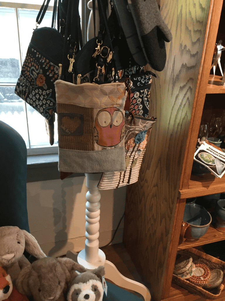 Colorful tote bags hanging on a stand in a cozy home decor setting.