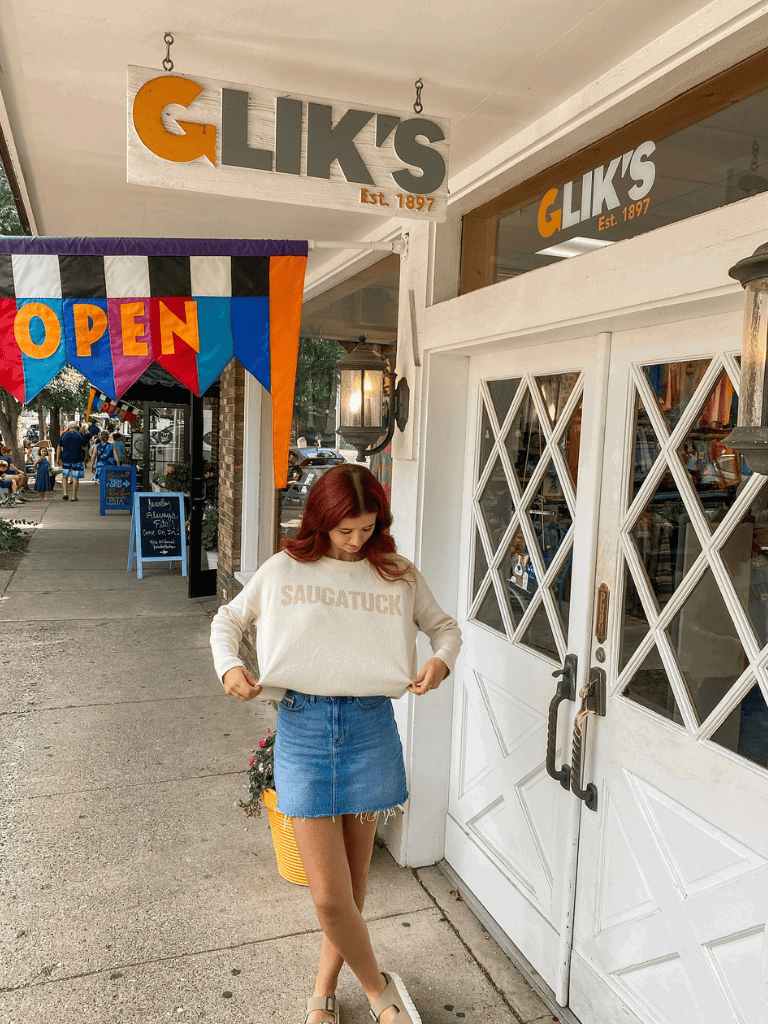 1. Woman standing outside GLIK'S store, shopping for fashion apparel on a vibrant sidewalk.