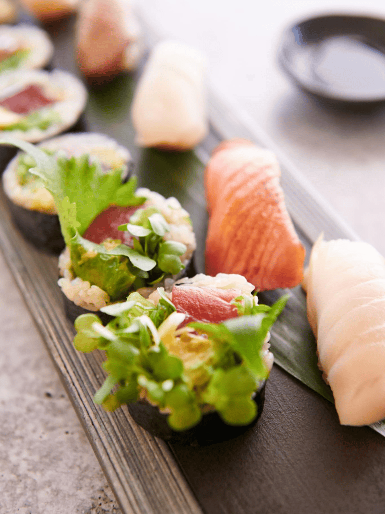 Fresh sushi rolls with seafood and vegetables on a black slate platter, colorful and appetizing.