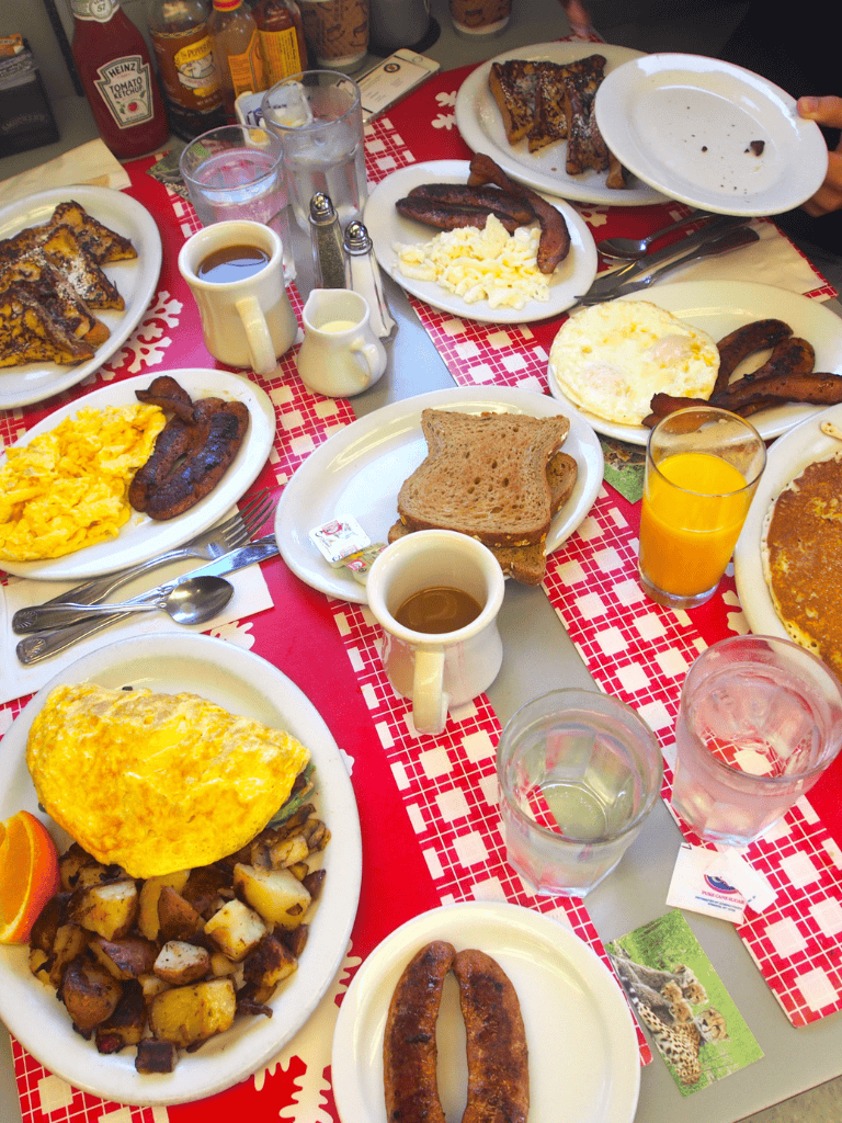 Scrambled eggs, bacon, toast, and breakfast drinks on a table at a cozy restaurant.