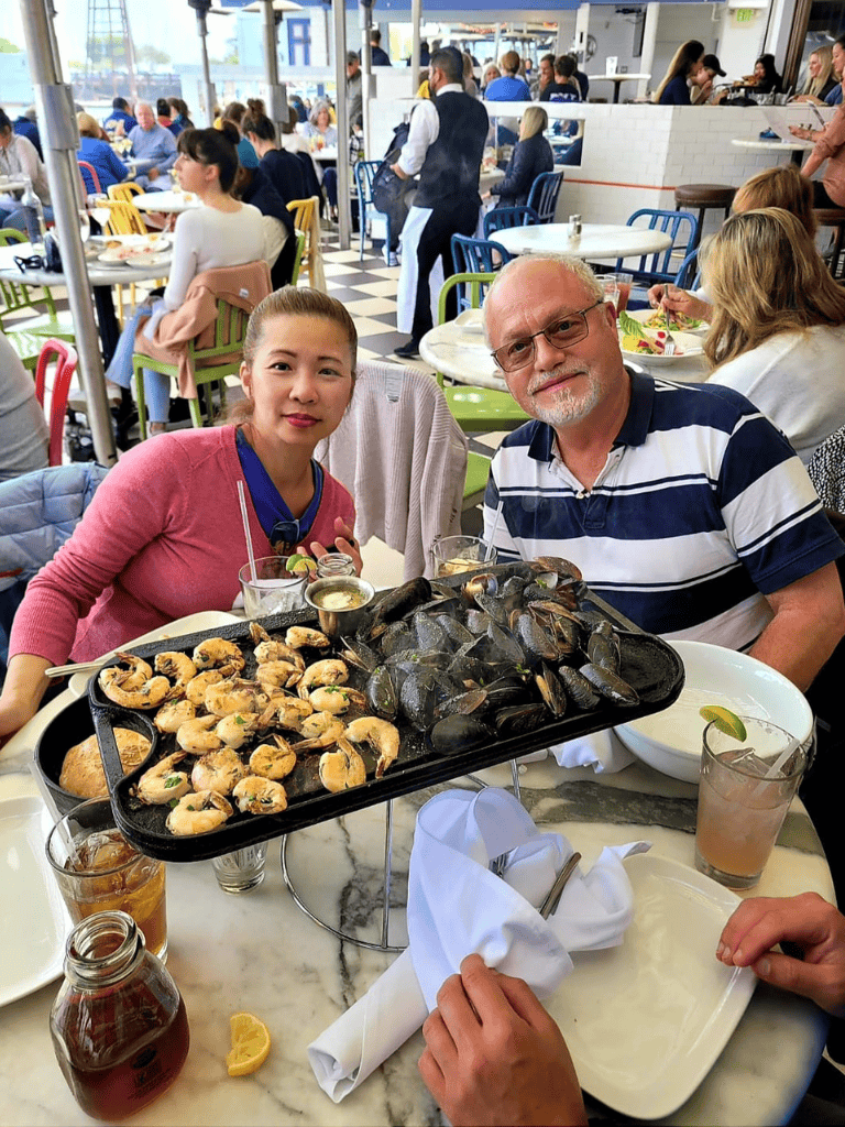 Fresh seafood at a lively restaurant, featuring mussels and shrimp, with happy diners enjoying their meal.