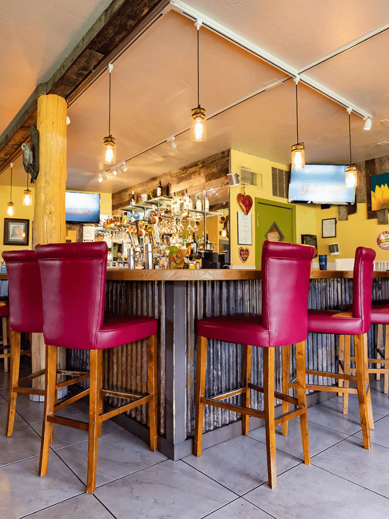 Comfortable bar seating with red leather chairs at a cozy restaurant bar.