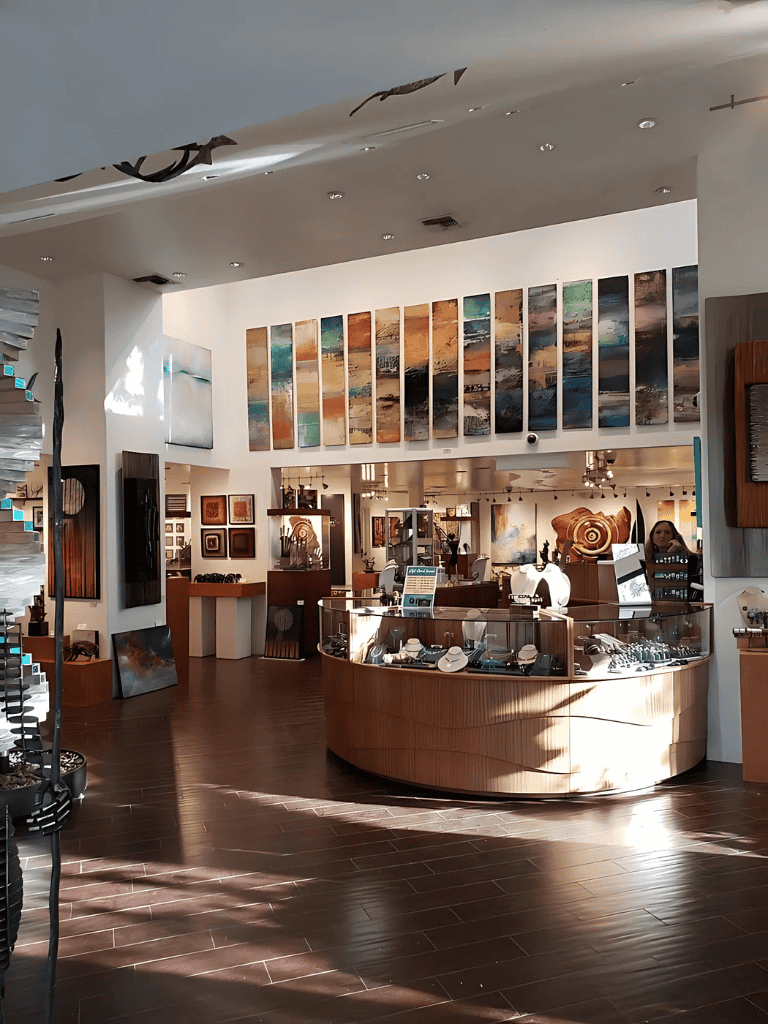 Colorful abstract art and jewelry display inside an art gallery or gift shop.