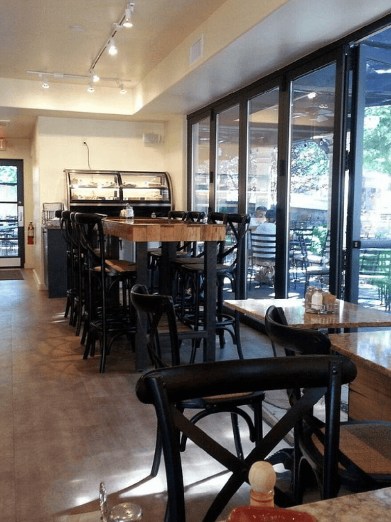 Cozy modern cafe interior with high-top tables and large windows for natural light.