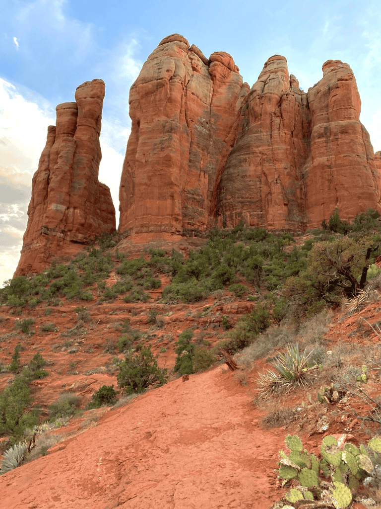 Vivid red rock formations at Cathedral Rock, Sedona, Arizona, with hiking trail and desert vegetation.