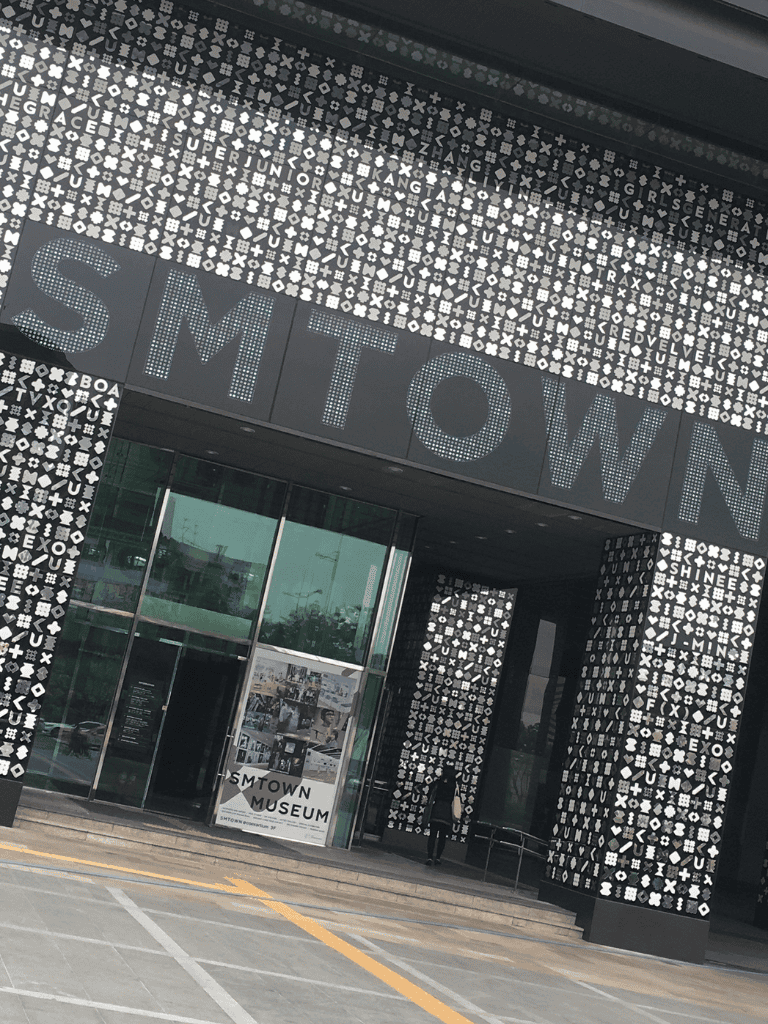 QuestForDirections, NYC SMTown Museum entrance, modern architecture, black and white mosaic exterior, cultural exploration, urban landmark.