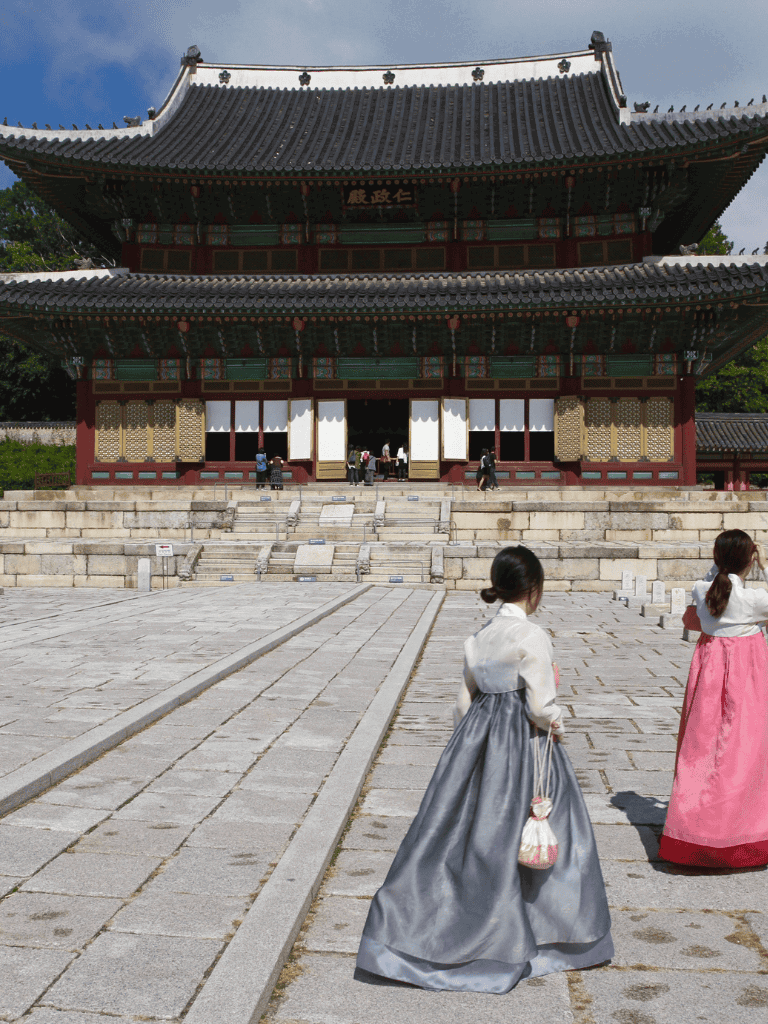 Traditional Korean temple architecture with visitors in hanbok attire.