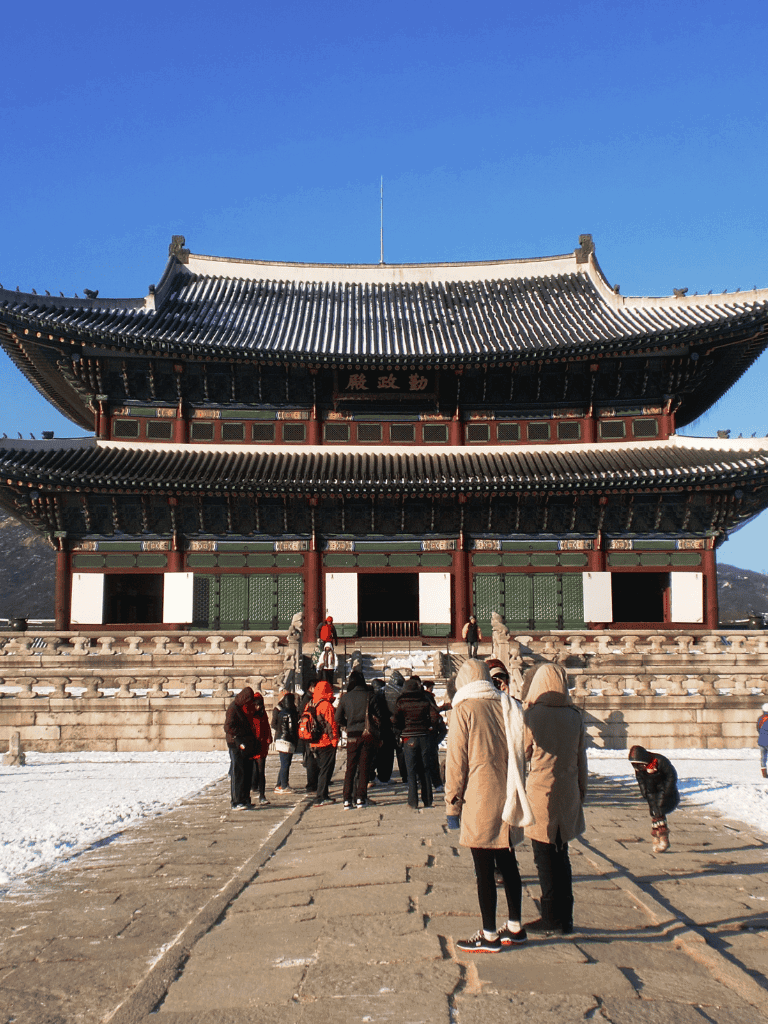 Ancient Korean palace with tourists and clear blue sky, scenic historical site, travel, cultural heritage.