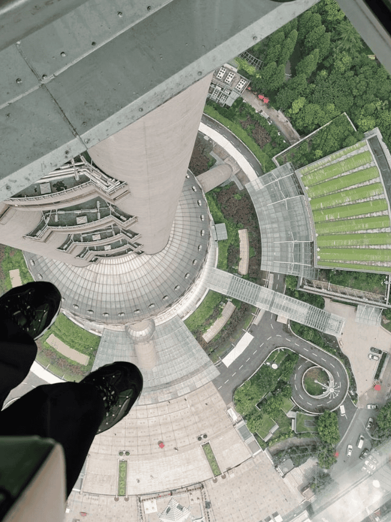 High-rise view looking down from skyscraper at QuestForDirections; modern urban architecture with glass and greenery.