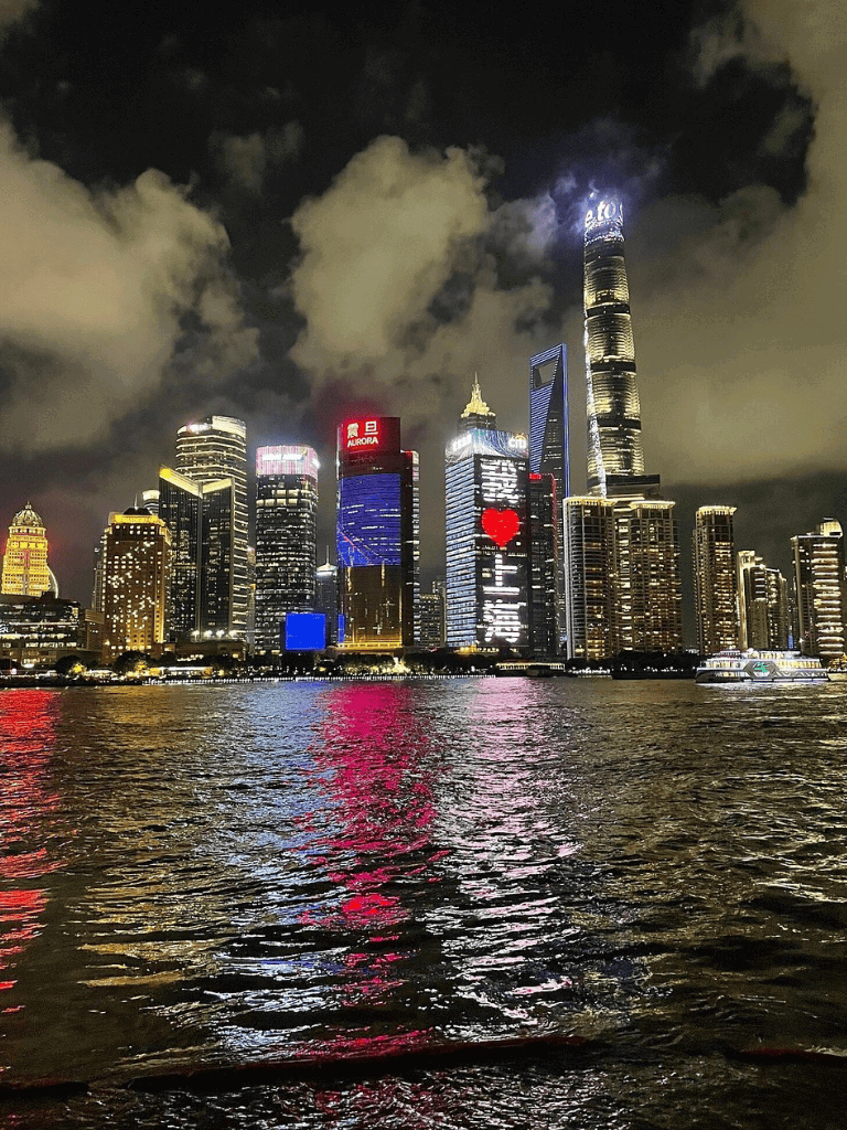Night city skyline with illuminated skyscrapers reflected in water, featuring the QuestForDirections logo for SEO.