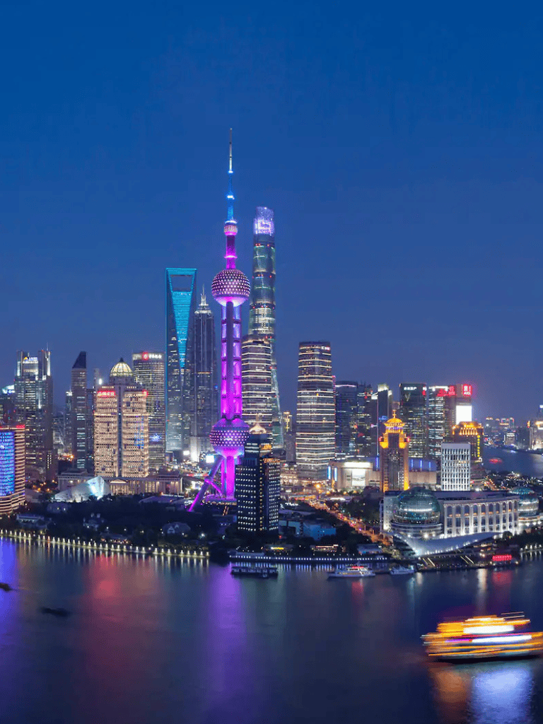 Bright Shanghai skyline with illuminated Oriental Pearl Tower at night, showcasing modern architecture and city lights.