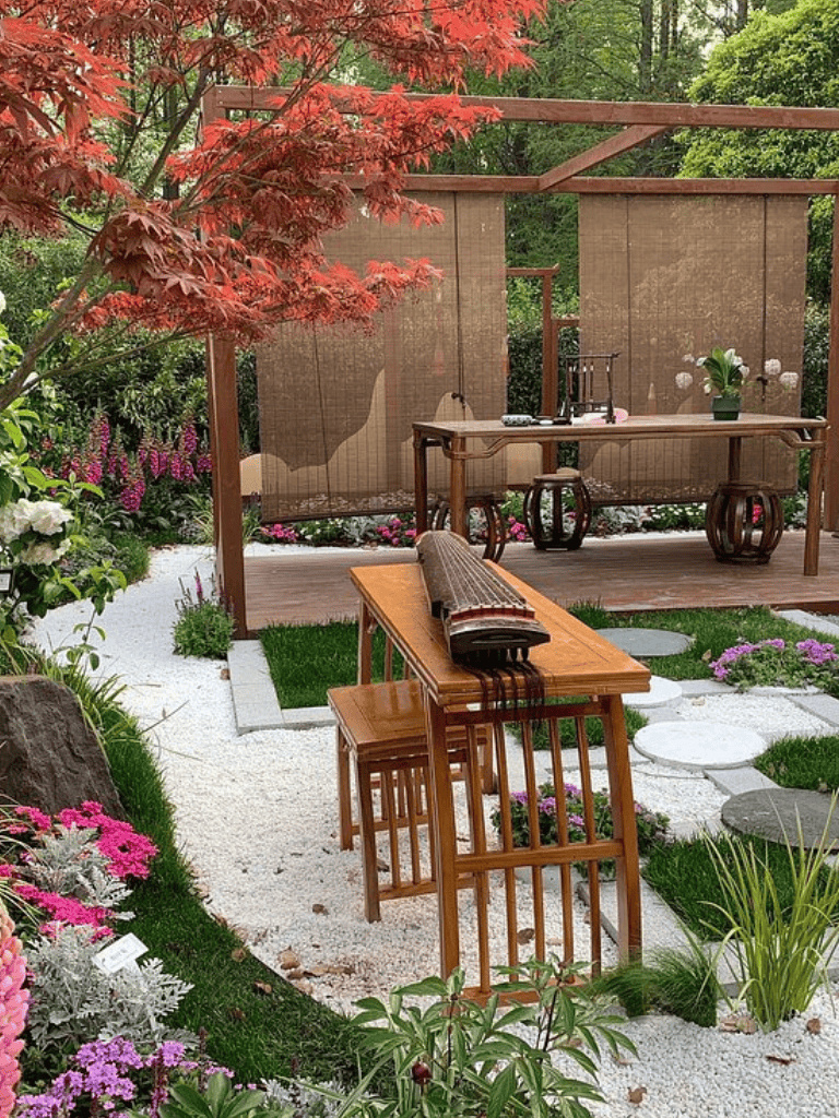 Elegant Japanese-inspired garden with bamboo privacy screen, wooden furniture, and colorful floral landscaping.