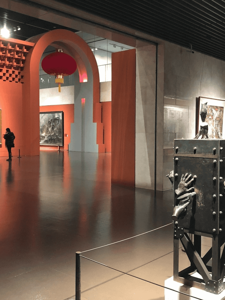 Vivid art gallery interior with sculptures and paintings on display, modern architecture and vibrant red accents.