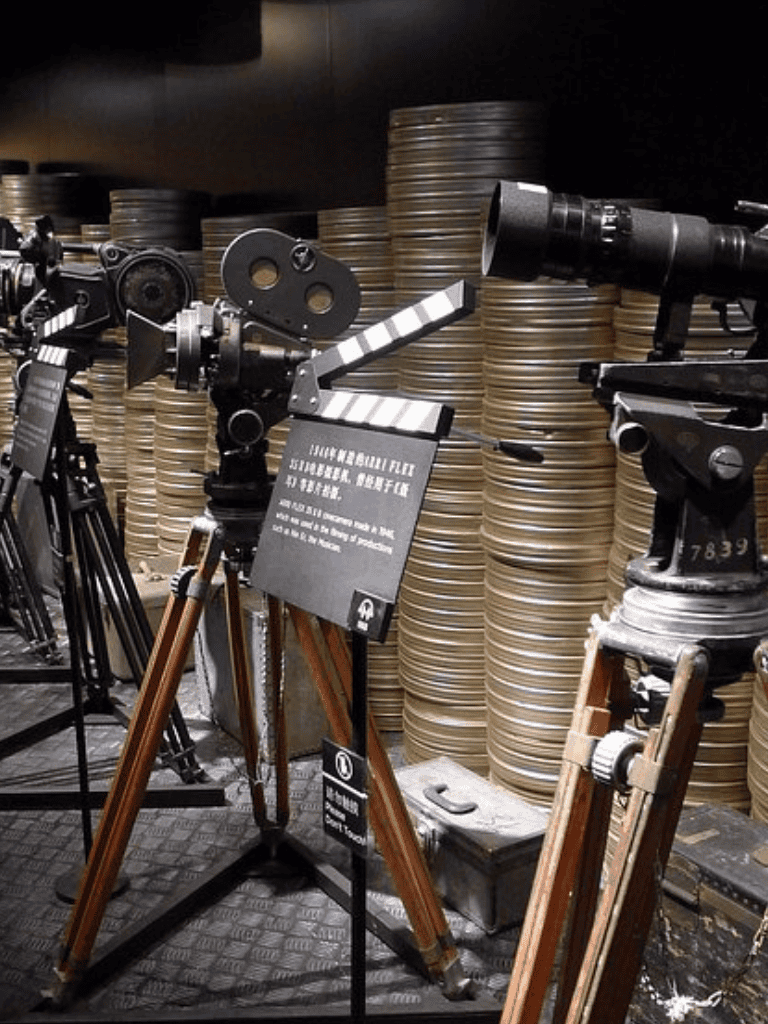 1. Vintage movie camera equipment displayed with film reels in the background.