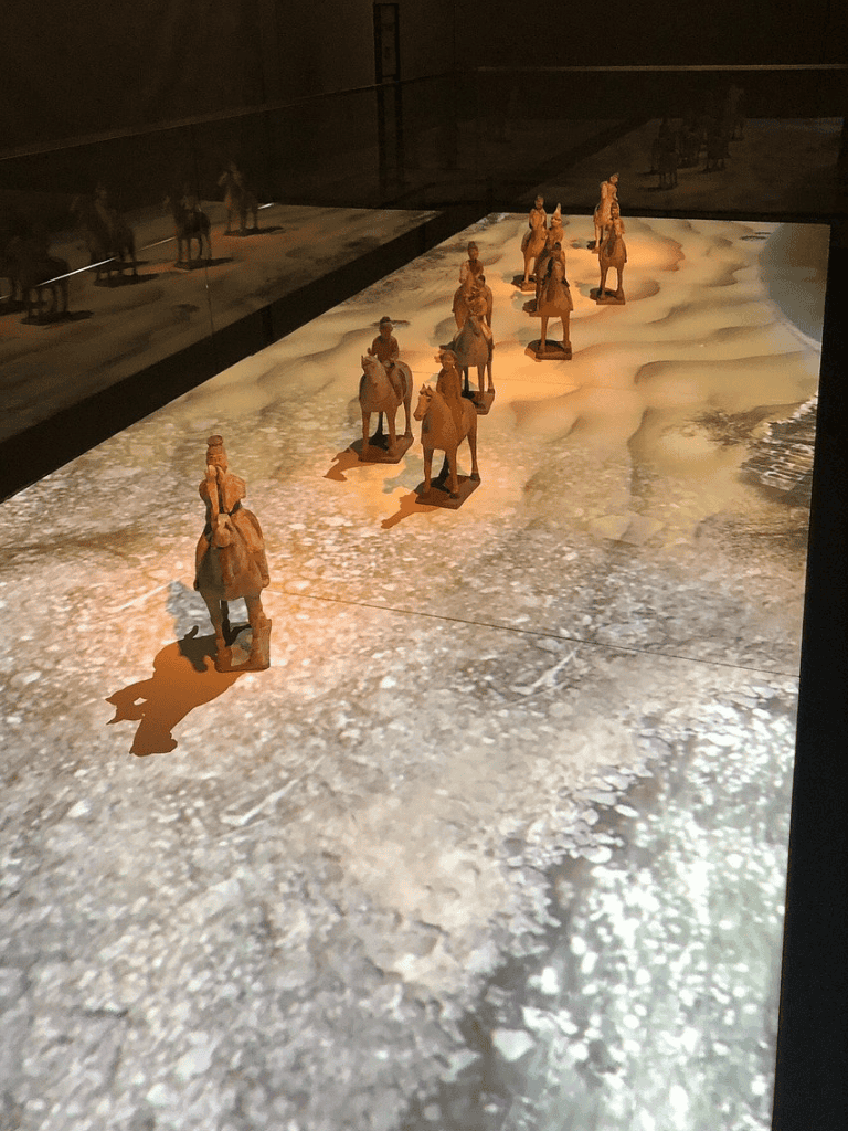 Brave explorers miniature figurines on desert terrain, immersive archaeological exhibit at Quest for Directions.