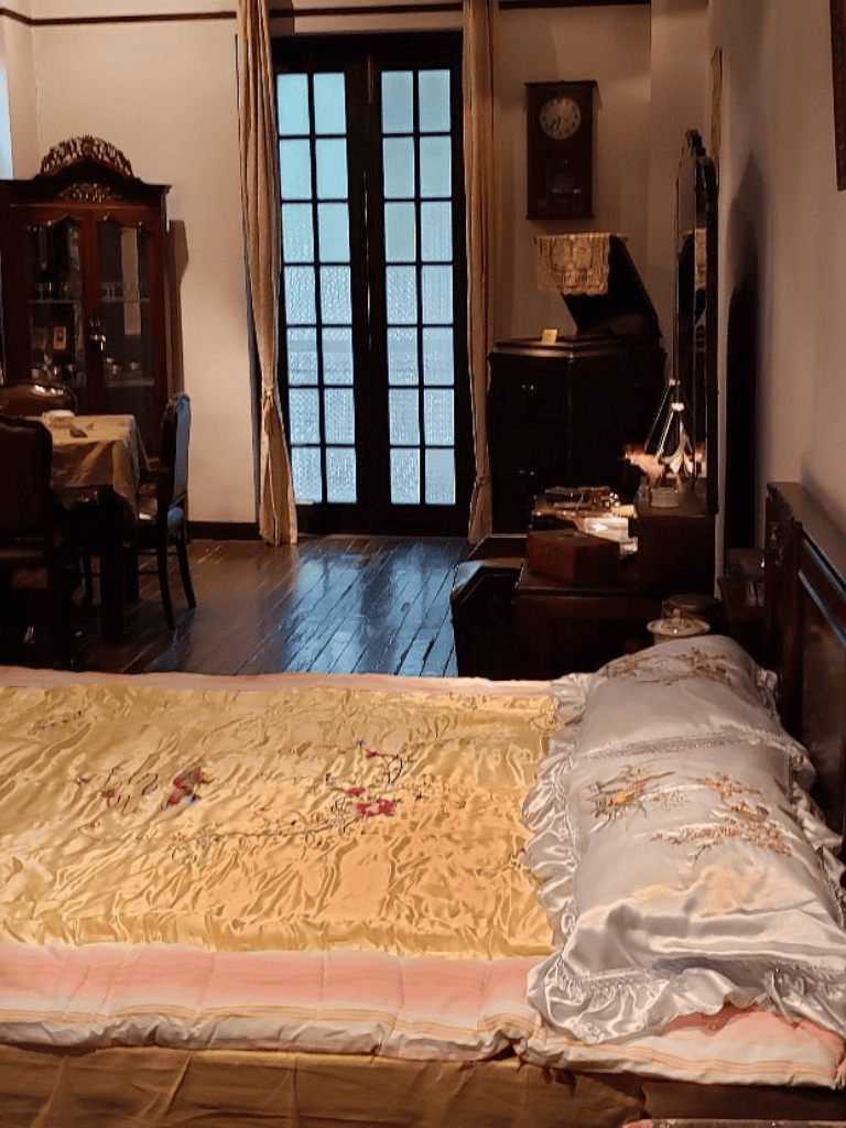 Cozy vintage bedroom with antique furniture and wooden flooring, next to glass doors and classic decor.