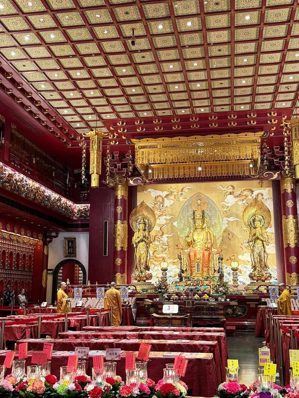 Intricate Buddhist temple interior with golden statues, vibrant decorations, and traditional incense offerings.